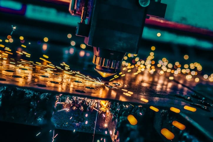A close-up of a CNC laser cutting machine in action, emitting sparks as it slices through metal, showcasing its vital role across various industries.