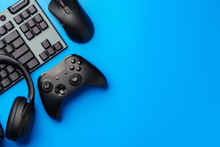 A sleek gaming setup featuring a keyboard, mouse, controller, and headphones on a blue background highlights the innovation within the tech industries.