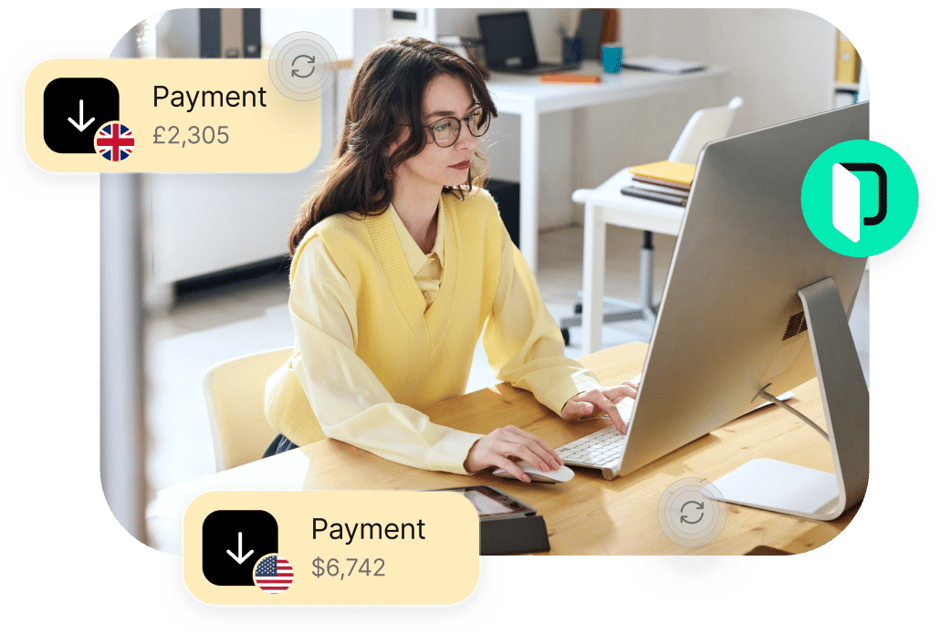 A person working at a desk on a computer with notifications of payments received: £2,305 from the UK and $6,742 from the US.